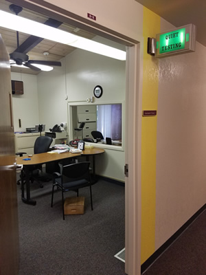 Room containing a desk and chairs, with a two-way mirror.