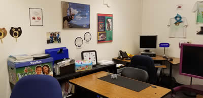 Room with a desk, chairs, computer, and decorative photos on the walls.