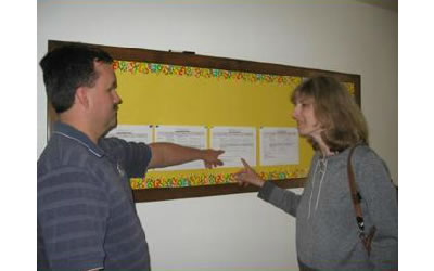 Katie's parents pointing at the schedule posted on the wall.