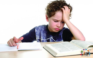 A discouraged boy glares at his homework and textbook.